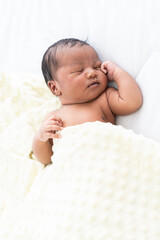 Top view of Newborn baby sleeping with blanket on white bed. Infant lying on white bed. African...