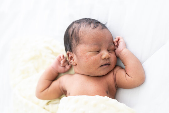 Top view of Newborn baby sleeping with blanket on white bed. Infant lying on white bed. African American newborn baby. Afro infant
