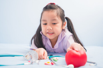 Happy cute girls in white medical uniform and stethoscope act like doctor. child dreams of becoming a doctor career concept