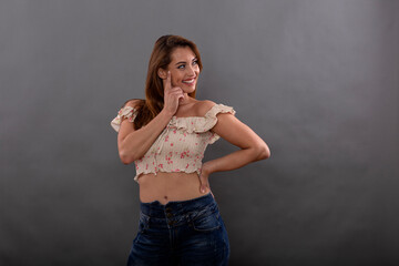 Cheerful brunette model dressed in summer clothes shows smile and happy emotions isolated on gray background