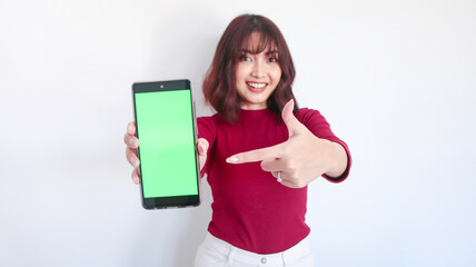 Naklejka premium Asian beautiful girl point on green screen phone with with blurry background on face in white background