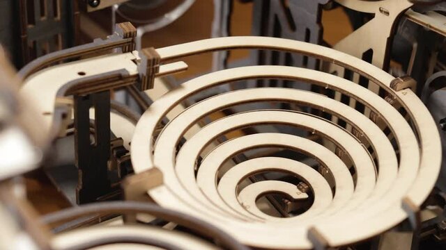 Battery-operated Marble Run. Silver Marbles Rolling On Wooden Spiral Track. close up