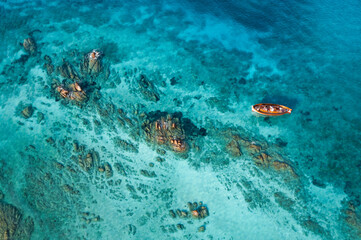 View from above, stunning aerial view of a wooden boat anchored to some rocks bathed by a crystal...