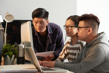 Serious university students in glasses testing new program they were working on and looking at computer screen