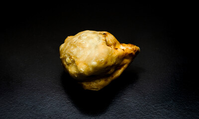 A homemade delicious fried samosa on a textured dark background