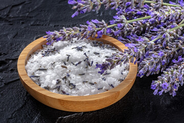 Lavender sea salt with a bunch of lavandula flowers, aromatic herb for cooking or a bath salt for spa, on a black background