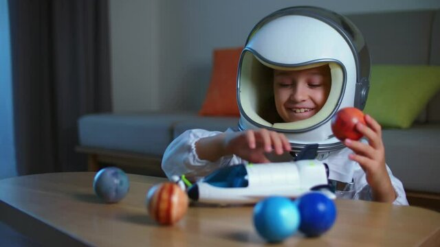 Funny portrait of a little girl 8-9 years old in a toy space suit, a smiling child, launches a space rocket, close-up, a pilot traveling in space. Child plays at home in an astronaut. Happy childhood