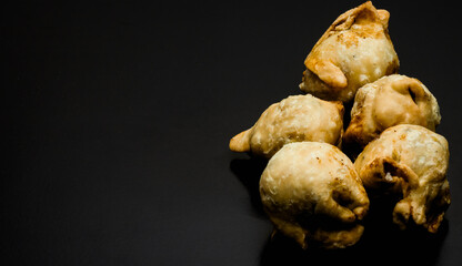 Homemade delicious fried samosas on a textured dark background with copy space