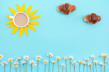 Creative concept of Good Morning. Coffee, croissants and chamomile flowers on a blue background....