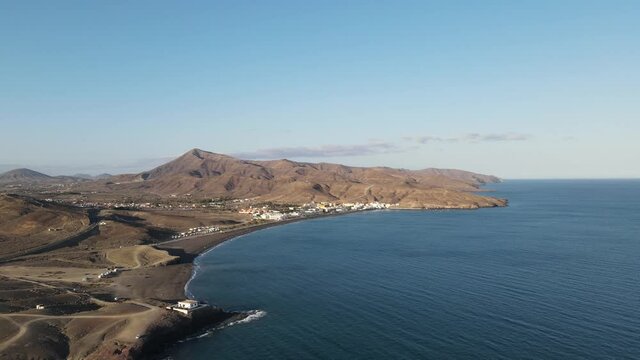 aerial drone video of a small village on the coast side of the island Fuerteventura while sunset.