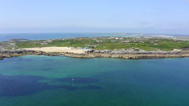 Beach at Kilkieran Bay, Ardmore, Connemara, County Galway, Ireland, July 2021. Drone faces west while orbiting and gradually ascending with views of the North Atlantic Ocean in the distance.