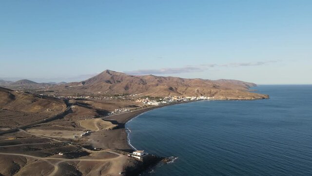 aerial drone video of a small village on the coast side of the island Fuerteventura while sunset.