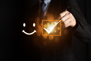Businessman holding digital with a checked box on excellent smiley face rating for a satisfaction...