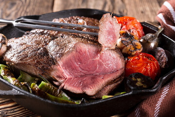 A piece of meat grilled in a cast-iron pan with vegetables