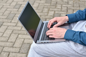 Laptop computer and man hands while working remotely on the computer outdoors.  Freelance programmer works remotely outdoors. Computer use for learning, online education concept.