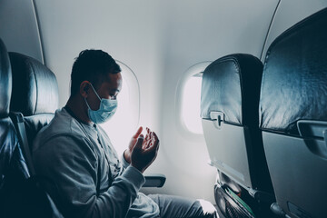 Muslim passenger in medical mask praying inside an airplane