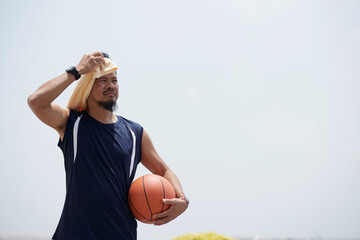 Basketball player wiping off sweat after from his forehead after training outdoors