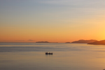 Obraz premium Silhouette of fishing boat sailing on the sea during sunset