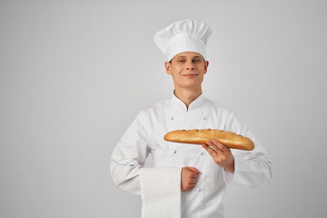a cook in a chef's uniform holds a loaf of baguette