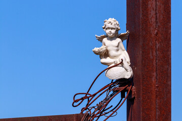 The statue of an angel near a rusty pillar