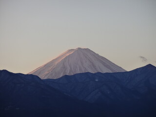 日の出の光に照らされる富士山
