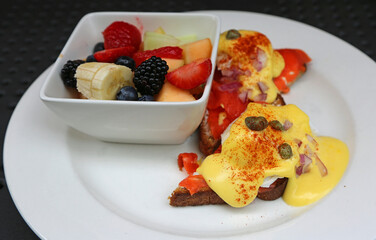 Eggs Benedict with salmon on bread with fruit cup