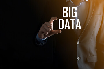 Businessman in a suit on a dark background holds the inscription BIG DATA. Storage Network Online Server Concept.Social network or business analytics representation