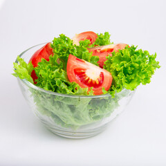 Green fresh salad of lettuce in glass dish on the white background