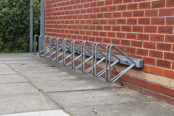 Empty bike rack, parking for bicycles against a red brick wall - 452444362