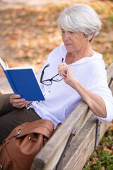 senior woman reading a book on the bench