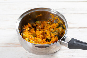 Cooking vegetable soup with eggplant and lentils in a saucepan on a table. Healthy veggie recipe