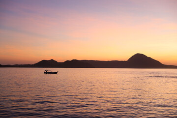 Naklejka na ściany i meble Black silhouette of hills with traditional fishing boat sailing on the sea at Labuan Bajo
