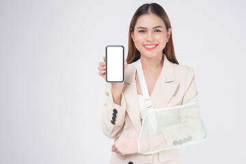 Portrait of young woman with an injured arm in a sling over white background in studio..