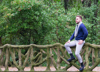 young man sitting on bridge with stone railing