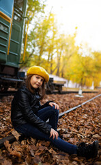 Cute little girl sitting on railway tracks. Crisp autumn day.	