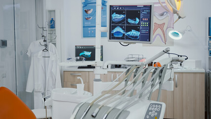 Close up revealing shot of medical orthodontic display with teeth xray images on it. Empty professional hospital stomatology chair with nobody in it equipped with dentistry tooth professional tools