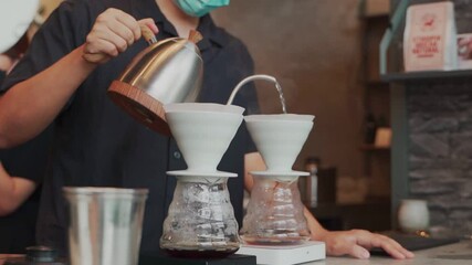 barista man making craft filter drip coffee at bar in coffee shop. pouring hot water and coffee to filtered cup for tasting sweet delicious. cupping note process by professional barista. hot water pot