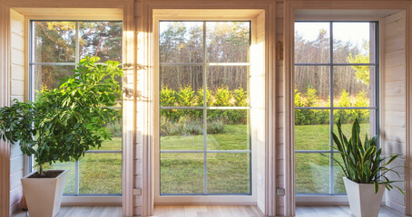 Bright interior of the room in wooden house with a large window overlooking the autumn courtyard....