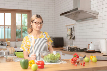 beautiful girl cooking at home preparing salad in kitchen.