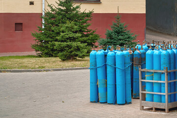 Naklejka premium Oxygen storage, equipment for medical breathing at medical facilities. Oxygen cylinder with compressed gas standing near hospital. Blue oxygen tanks for medical industry