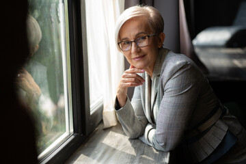 portrait of stylish adult woman in gray suit near window 