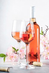Rose wine glass and bottle on the gray table and pink flowers. Rosado, rosato or blush wine tasting