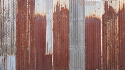 Rusty old galvanized wall. Patterned background of old red and gray metal fence plaques. Selective focus