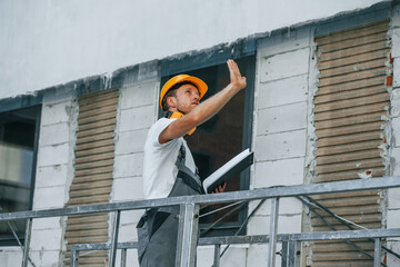 Unfinished project. Young man working in uniform at construction at daytime
