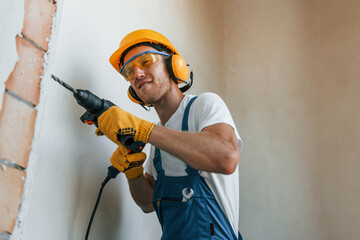 Modern repair. Young man working in uniform at construction at daytime