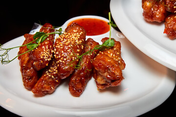 Sesame fried chicken wings with sauce and parsley. Close-up, selective focus.