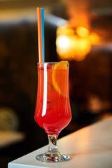 Red alcoholic cocktail with ice and straw. Close-up, selective focus