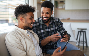 Young student brothers in kitchen indoors at home, using smartphone.