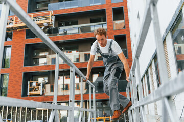 Building exterior. Young man working in uniform at construction at daytime