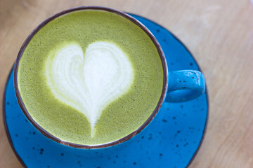 delicious and hot matcha latte with decorative heart in a cup close-up, vegan Japanese trending...